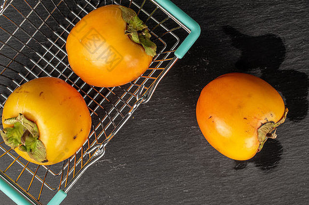 集团甜蜜的橙色柿子购物篮子平铺灰色石头