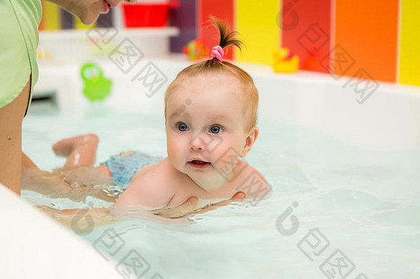 婴儿学习游泳婴儿游泳健康的家庭妈妈。教学婴儿游泳池