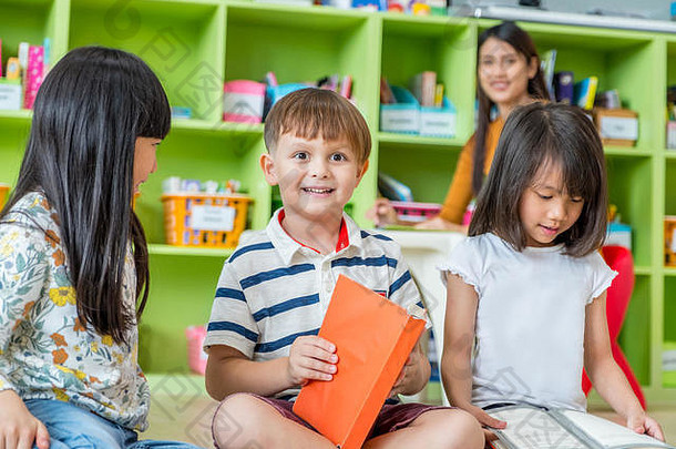 孩子们坐着地板上阅读演讲书学前教育图书馆老师幼儿园学校教育概念