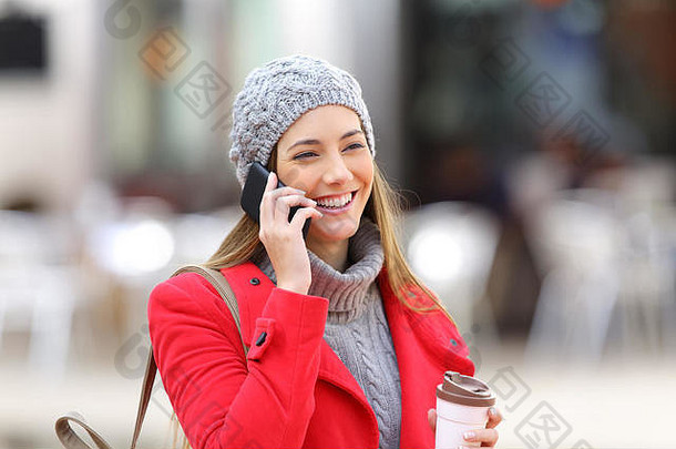 快乐女人调用移动电话持有咖啡街冬天