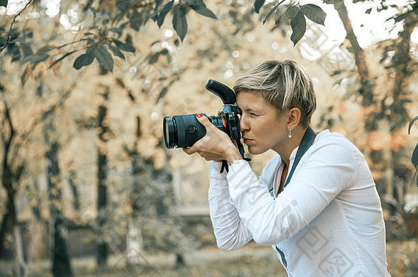 专业女人摄影师采取相机户外肖像主要的镜头摄影自然绿色植<strong>物语</strong>气