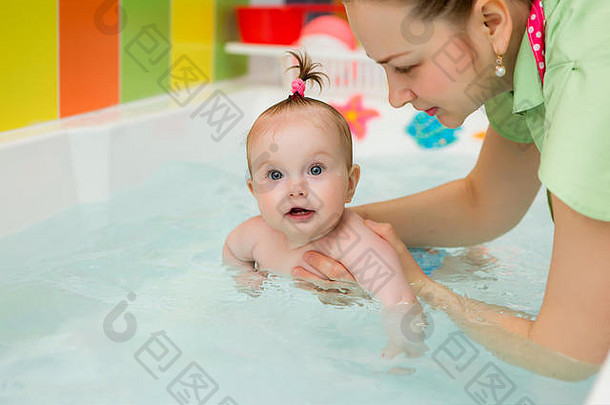婴儿学习游泳婴儿游泳健康的家庭妈妈。教学婴儿游泳池