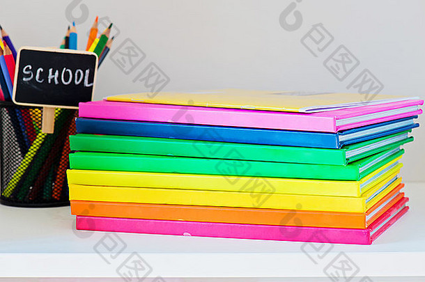 多彩色的书堆栈浅色书架上铅笔情况下背景