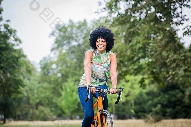 前面视图成熟的女人非洲式发型骑自行车微笑