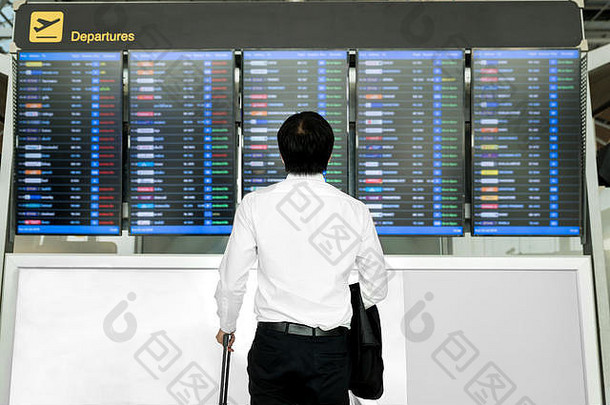 业务旅行概念亚洲年轻的业务男人。行李等待旅行机场飞行时间表