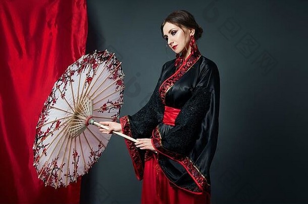 女人穿着红色的中国人日本人服装飞行织物美丽的伞风扇日本中国人风格长耳环耳朵