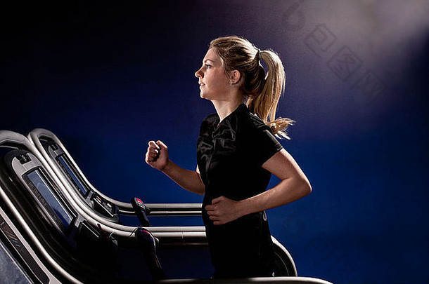 年轻的女人运行跑步机健身房高度中心