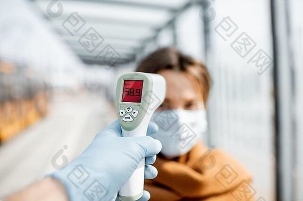 测量温度红外温度计年轻的女人脸面具检查点疫情在户外概念预防传播病毒