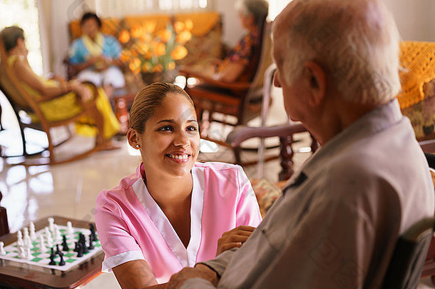 人老年临终关怀年轻的有吸引力的拉美裔女人工作护士需要护理高级男人。轮椅