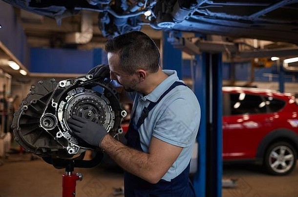 腰肖像肌肉发达的车机械师检查齿轮箱汽车修复商店复制空间