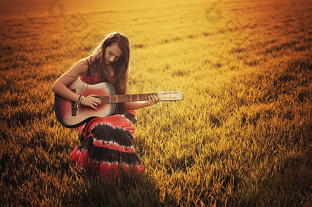 微笑女孩坐着草地日落玩吉他波兰