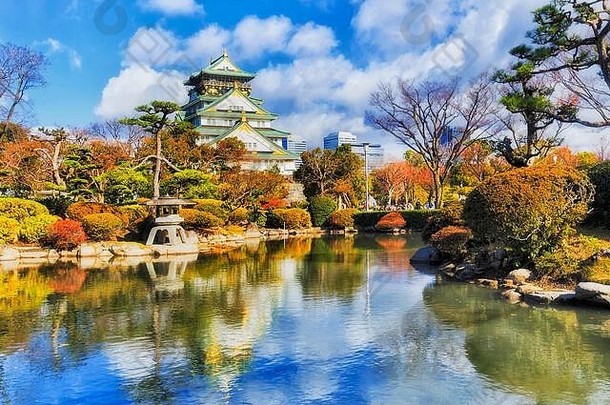 美丽的大阪城堡中间绿色秋天的花园池塘反映颜色传统的日本体系结构蓝色的天空