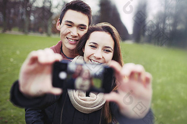 年轻的夫妇快乐采取图片聪明的电话公园十几岁的男孩女孩爱拍摄