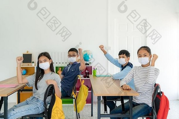 集团亚洲小学学校学生穿卫生面具教室手臂提高了快乐回来学校重开学校规范
