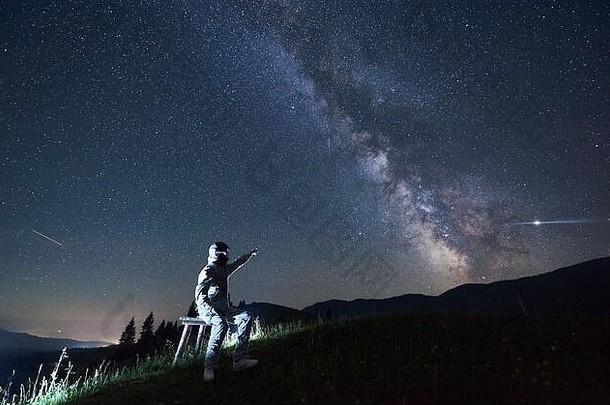 照亮男人。白色空间西装头盔坐着凳子山指出乳白色的明亮的极地明星拍摄星星布满星星的天空晚上概念空间旅行宇宙航行学