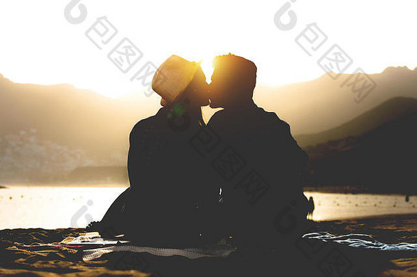 浪漫的年轻的夫妇接吻海滩日落轮廓青少年情人开始故事坐着沙子