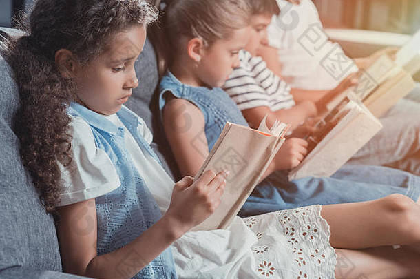 多元文化的集团集中孩子们阅读书坐着沙发首页