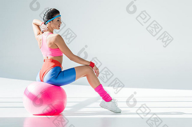 运动年轻的女人坐着锻炼健身球灰色