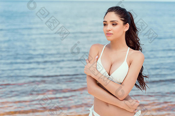 有吸引力的女孩摆姿势白色比基尼海滩海