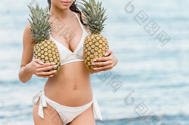 部分视图有吸引力的女人白色比基尼持有新鲜的菠萝