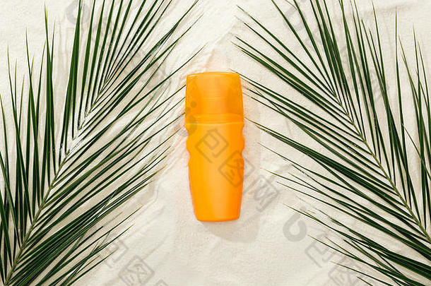 前视图棕榈叶子橙色防晒霜沙子