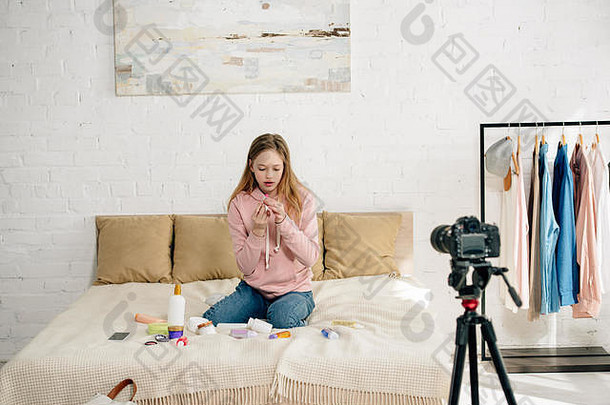 十几岁的孩子牛仔裤坐着床上化妆品前面视频相机
