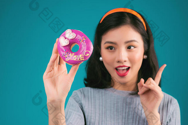 亚洲美女孩持有粉红色的甜甜圈复古的快乐的女人糖果甜点站蓝色的背景