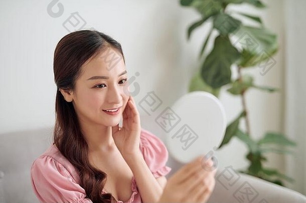年轻的亚洲女人持有镜子生活房间
