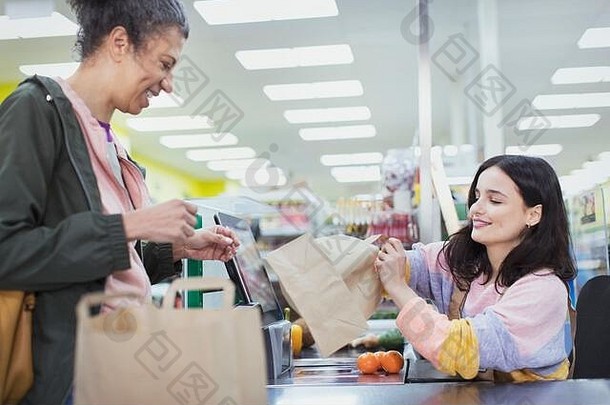 女收银员帮助客户袋食品杂货超市结帐