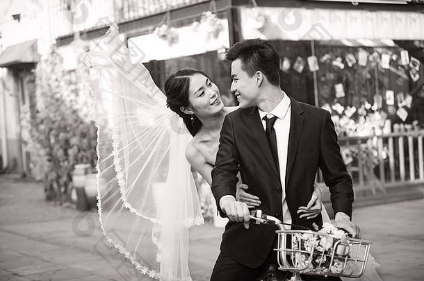 浪漫的亚洲新结婚夫妇有趣的骑自行车黑色的白色