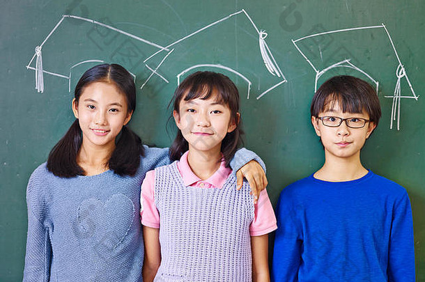亚洲小学学校孩子们站前面黑板下面chalk-drawn博士帽