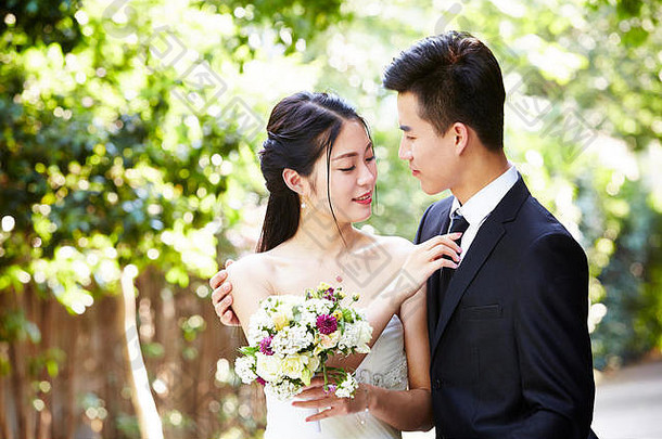年轻的亚洲新郎接吻新娘在户外婚礼仪式