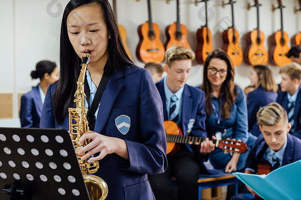 青少年学生玩萨克斯风学校音乐教训休息类背景焦点
