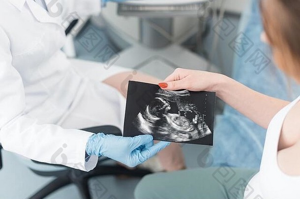 裁剪视图医生给超声波扫描年轻的怀孕了女人诊所