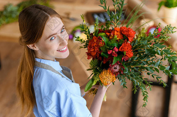 高角视图美丽的年轻的花店持有花束花微笑相机