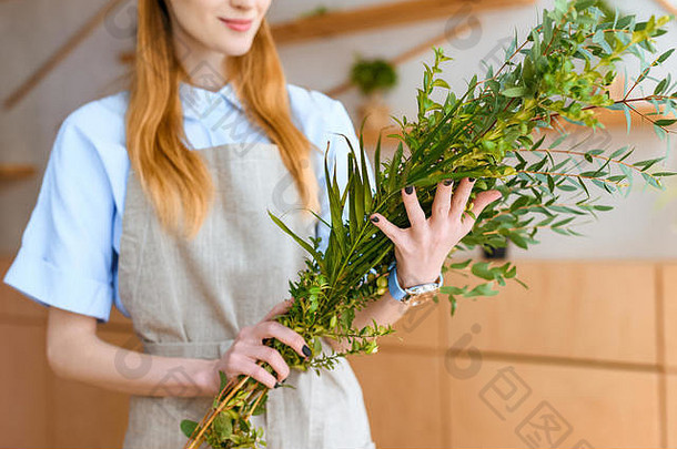 裁剪拍摄微笑年轻的花店围裙持有绿色植物