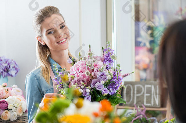 有吸引力的微笑女人围裙持有花束花商店
