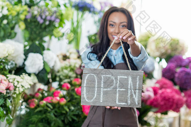 美丽的非洲美国花店持有开放标志微笑相机