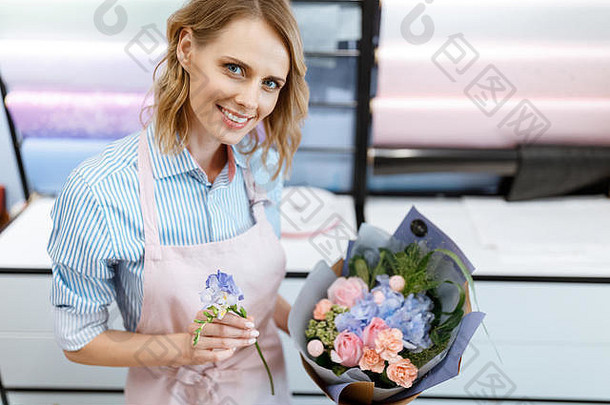 微笑年轻的花店安排花束相机花商店