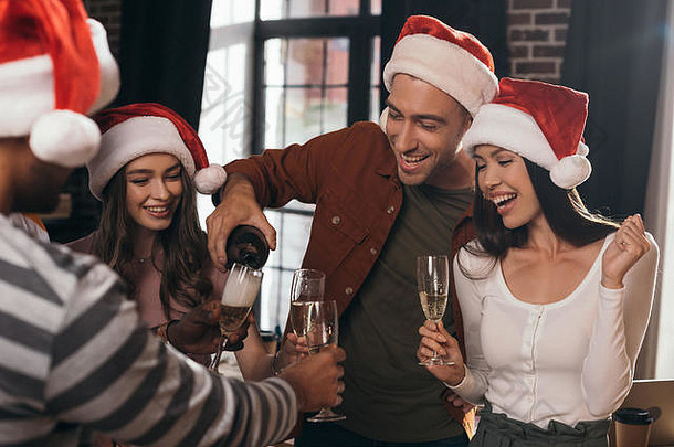 快乐的商人倒香槟眼镜快乐的同事们圣诞老人帽子