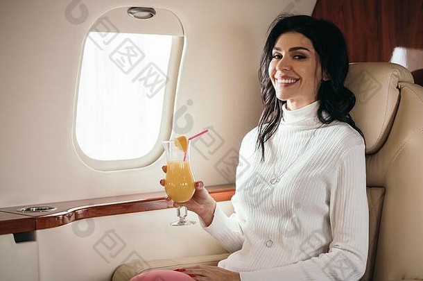 快乐的女人持有美味的鸡尾酒私人飞机