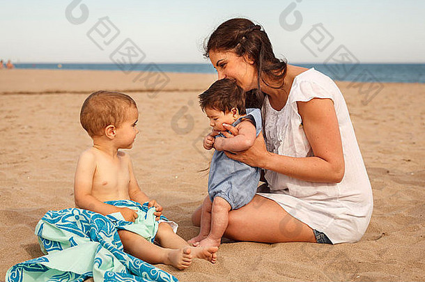 妈妈。婴儿坐着海滩