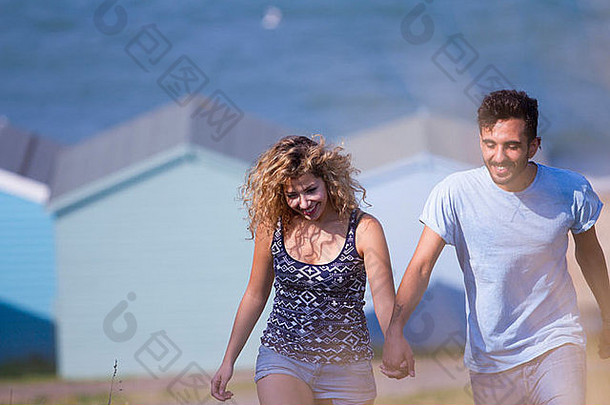 年轻的夫妇持有手海滩小屋背景