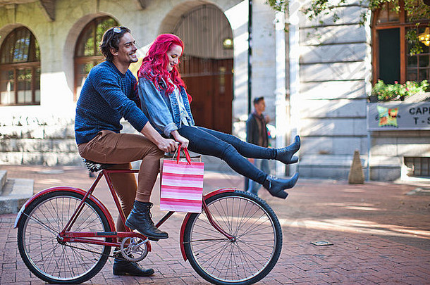 年轻的女人坐着男朋友自行车车把角小镇南非洲