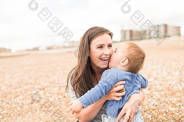 妈妈。年轻的儿子玩卵石海滩