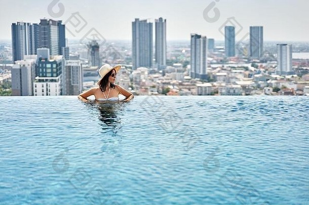 年轻的女人享受夏天假期屋顶前游泳池