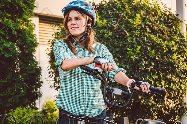 肖像快乐的女孩持有移动电话快乐微笑学生自行车分享应用程序聪明的电话户外城市生活