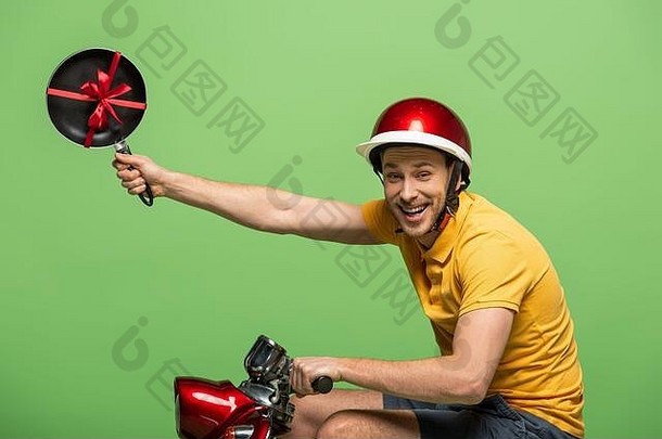 一边视图快乐交付男人。黄色的统一的持有煎锅弓踏板车孤立的绿色