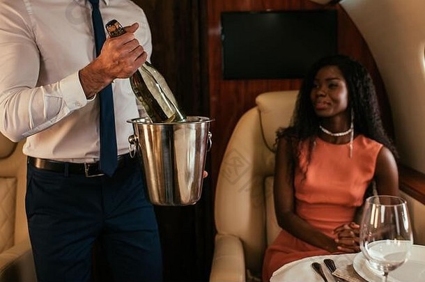 裁剪视图空气管家持有香槟桶瓶优雅的非洲美国女人