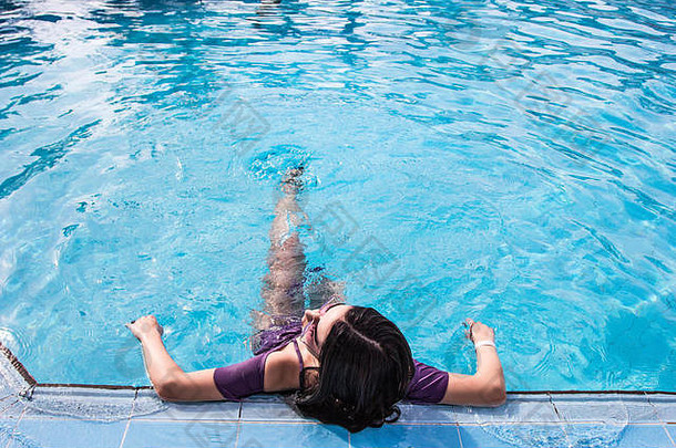 高角视图美丽的年轻的女人休息游泳池
